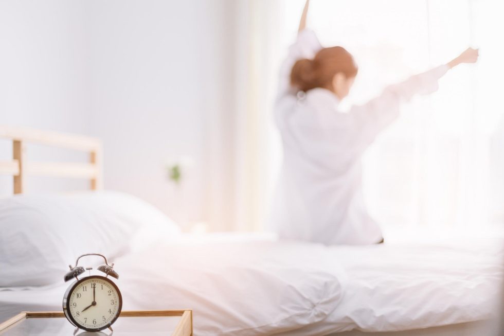 Une femme s'étire au réveil devant la fenêtre